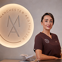 Sam standing at the Manchester Aesthetics clinic reception in professional uniform